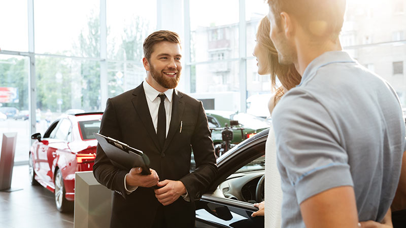 A salesman talking with a couple at a dealership